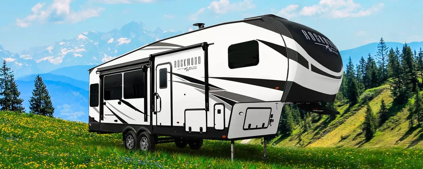 Rockwood RV sitting on a hill with an outdoor landscape of mountains and trees behind it.